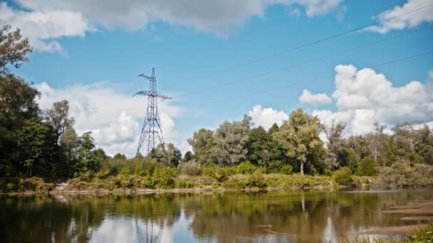 Brede shot timelapse van elektriciteitskabels en hoogspanning pylonen op een veld in het platteland op de zomer in de buurt van rivier — Stockvideo