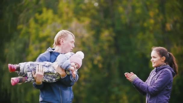 Familia feliz: Padre, Madre e hijo - niña caminando en el parque de otoño: jugando y aplaudiendo, cámara lenta — Vídeo de stock