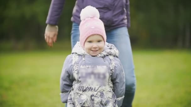 Gelukkige familie: moeder en kind - meisje, wandelen in de herfst park: baby dicht omhoog, slow-motion — Stockvideo