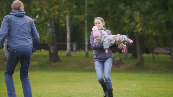 Happy family: Father, Mother and child - little girl walking in autumn park: running and playing at the grass — Stock Video