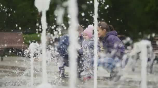 Familia feliz - madre, padre e hija pequeña cerca de fuentes en el parque de la ciudad - niña tocando el agua — Vídeo de stock