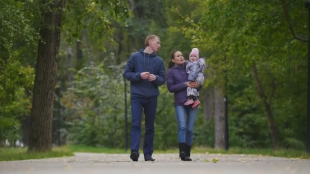 Gelukkige familie: vader, moeder en kind - meisje in herfst park: wandelen in de buurt van bomen — Stockvideo