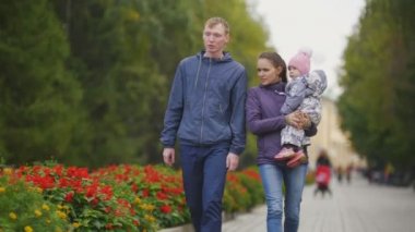 Mutlu bir aile: Baba, anne ve çocuk - sonbahar Park küçük kız: çiçekli sokakta yürüyor