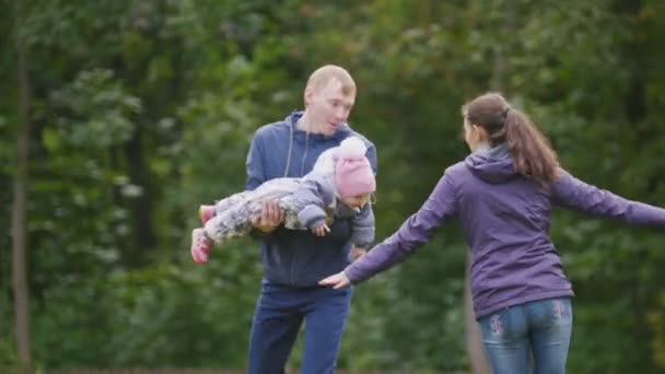 Szczęśliwa rodzina: ojciec, matka i dziecko - dziewczynka spaceru w parku jesień: matka gry samolot — Wideo stockowe