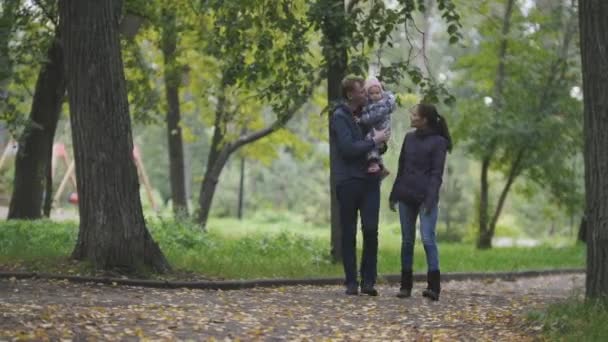 Happy family: Father, Mother and child - little girl in autumn park: walking through the alley with the fallen leaves, wide ungle — Stock Video