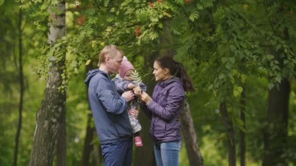 Szczęśliwa rodzina: ojciec, matka i dziecko - dziewczynka w jesienny park: tata, mamusia i baby pozowanie wokół Rowan — Wideo stockowe