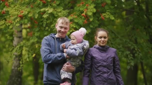 Gelukkige familie: vader, moeder en kind - meisje in herfst park: Papa, mammy en baby poseren rond Rowan, close-up — Stockvideo