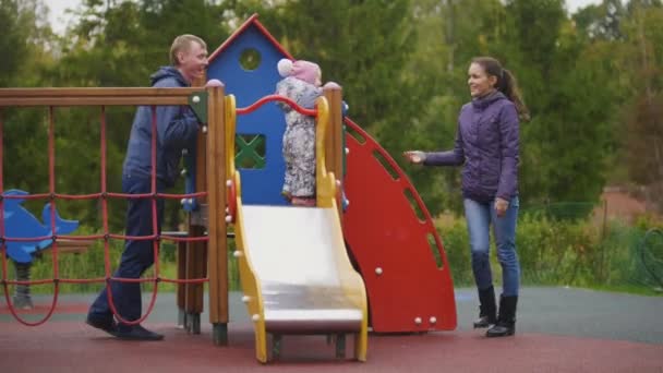 幸せな家族: 父、母と子 - 秋の公園で歩く少女: マミーポコ、お父さんと赤ちゃんの遊び場で遊ぶ — ストック動画