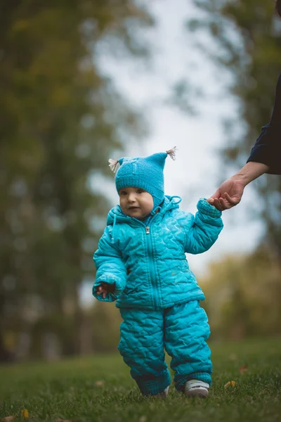Familia feliz caminando en el parque de otoño: un niño corre en el campo con la ayuda de la madre — Foto de Stock