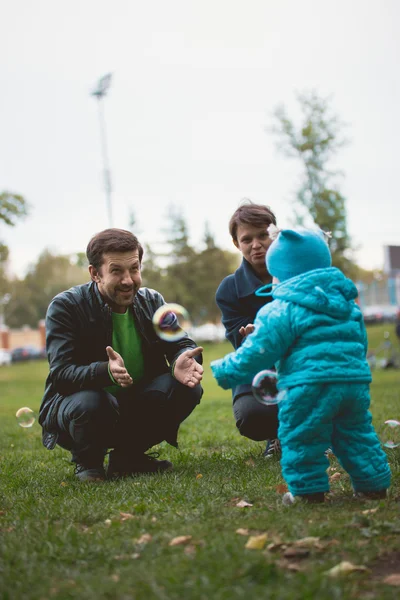 La familia feliz que camina en el parque otoñal: la mamá, el padre y su hijo pequeño - aprendan a pasear independientemente — Foto de Stock