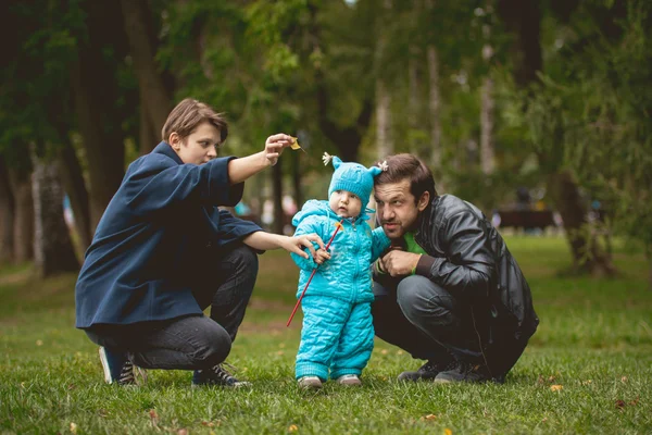 Familia caminando en el parque de otoño mamá le muestra a su hijo un juguete — Foto de Stock
