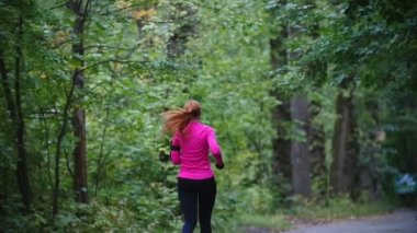 Runner genç kadın sonbahar park açık havada egzersiz yağmur, pembe eğitim takımı, dikiz, ağır çekim çalıştırmak için