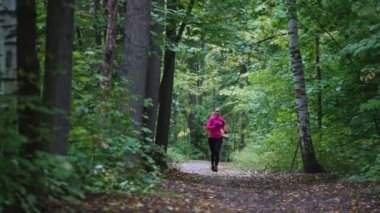 Runner genç kadın sonbahar park açık havada kasvetli hava - yağmur, parlak pembe eğitim takım, egzersiz içinde çalışan yakın çekim
