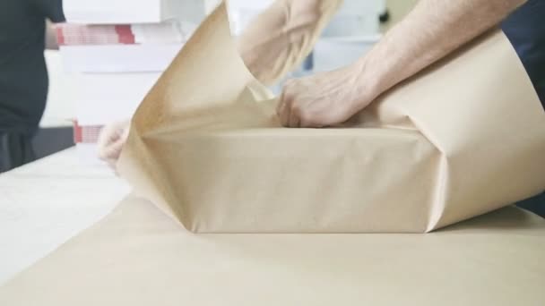 Закрыть руки мужчин упаковка коробки из ленты в полиграфической промышленности — стоковое видео