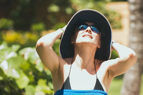 Retrato de mujer joven y hermosa en gafas de sol sombrero en un día soleado en la playa tropical, cielo que se asoma —  Fotos de Stock