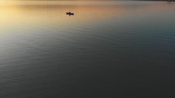 Hombre navegando en el barco con remos en el río al atardecer — Vídeos de Stock