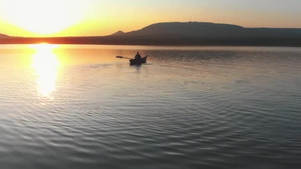 Hombre navegando en el barco con remos en el río mientras el atardecer — Vídeos de Stock