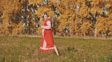 Sonbahar tarlasında kılıçla poz veren militan kadın.