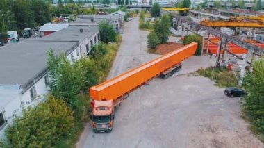 Vinçlerin turuncu parçalarını fabrikadan kamyona yüklüyorlar.