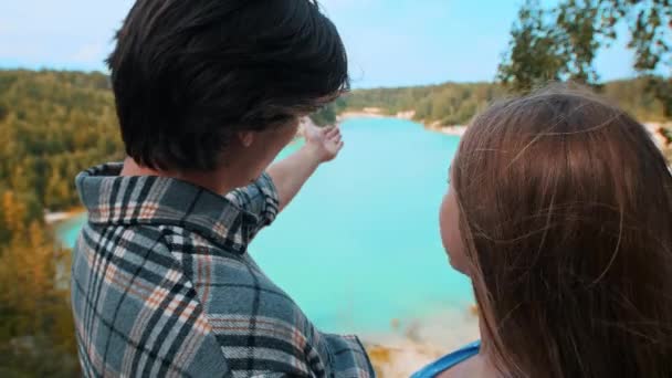 Młoda szczęśliwa para mówi tło niebieskiego jeziora i lasu - pocałunek — Wideo stockowe