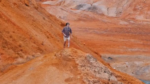 Νεαρός που περπατάει σε πορτοκαλιές βουνοκορφές, σηκώνει τα χέρια ψηλά. — Αρχείο Βίντεο