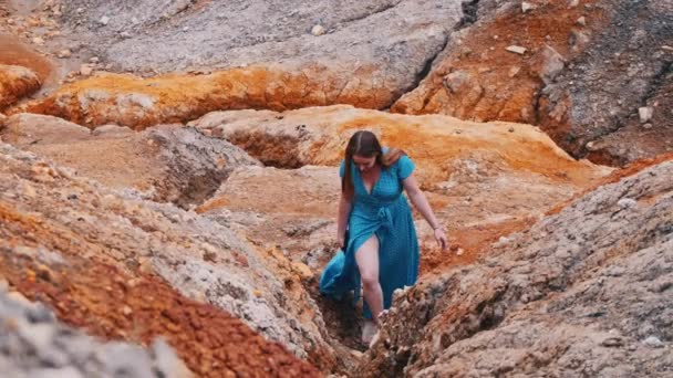 Jeune femme en robe marchant sur une vallée d'argile orange — Video