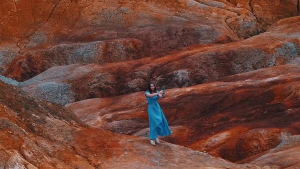Jonge vrouw in blauw jurk het nemen van een selfie op een klei heuvels — Stockvideo