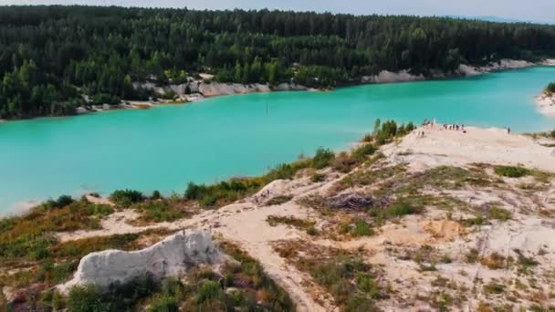 Landskap av en ljusblå sjö omgiven av sand - människor som står på en kulle sand — Stockvideo