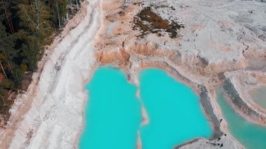 Kum ve kayalarla çevrili açık mavi bir göl manzarası