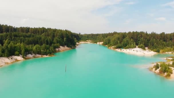 Landschaft eines hellblauen Sees, umgeben von grünen Wäldern und Sandhügeln — Stockvideo