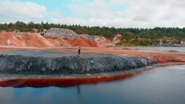 Turuncu kil vadide yürüyen bir adam - alışılmadık kırmızı su ve dağ manzarası — Stok video