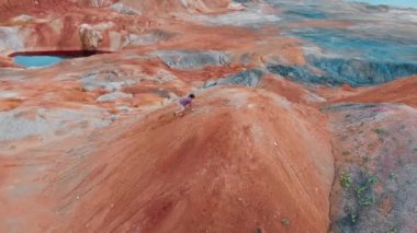 Turistin biri turuncu kil bir dağda koşuyor.