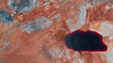 Bir adam kanlı kırmızı gölden sürünerek uzaklaşıyor.