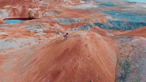Um turista homem correndo em uma montanha de barro laranja — Vídeo de Stock