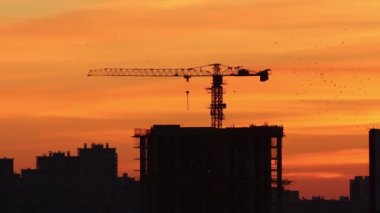 Kırmızı ve turuncu tonlarda sabah gökyüzü - binaların siluetleri ve vinç kaldırma