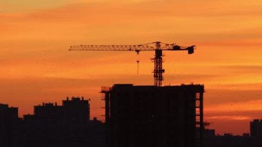 Erken şafak - kırmızı ve turuncu tonlarda sabah gökyüzü - binaların siluetleri ve vinç kaldırma