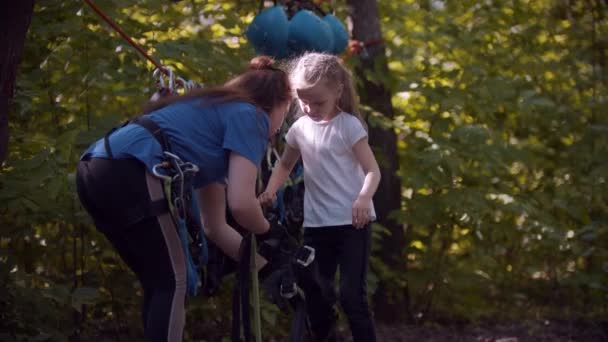 Inspector puts on a protective system on the girl before the attraction in the forest — Stock Video