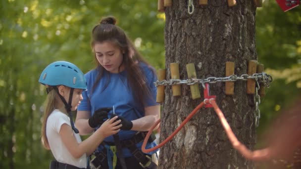 巡视员向那姑娘解释如何在绳子上系上一个保护钩- -在树的最高处，这是一次极端的冒险 — 图库视频影像