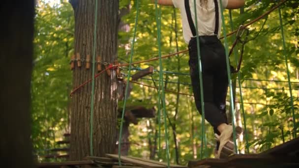 Une femme marche sur les marches suspendues entre les arbres une aventure extrême de corde — Video