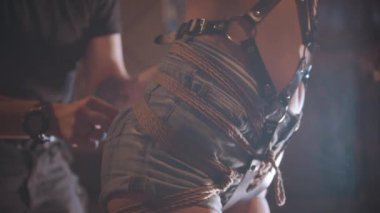 Erkekler, BDSM antrenmanı için kadınların kalçalarına ip bağlar.