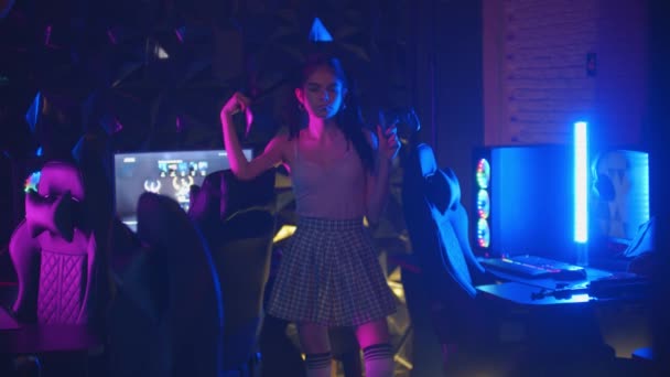 年轻性感大胆的女人，留着马尾辫，在霓虹灯游戏俱乐部里拿着操纵杆，吹着泡泡糖 — 图库视频影像