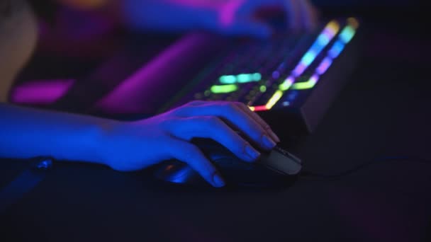 Young woman playing online games in neon gaming club - mouse and highlighted keyboard — Stock Video