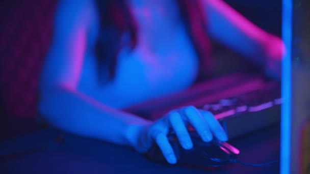 Junge hübsche Frau mit Brille spielt Online-Spiele im Neon-Gaming-Club - trägt Kopfhörer und spricht ins Mikrofon — Stockvideo