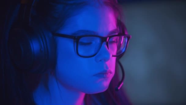 Wanita cantik berkacamata bermain game di klub game neon modern dan mengunyah permen karet — Stok Video