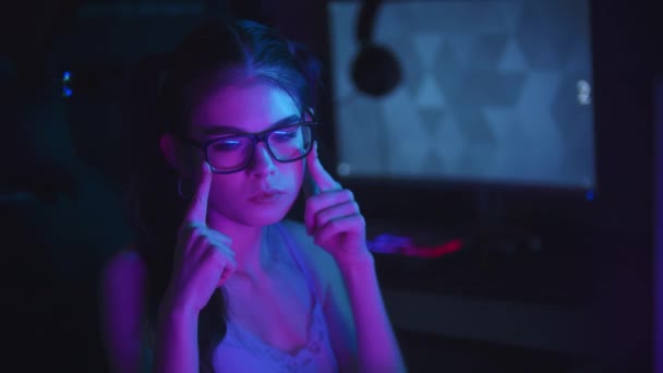 Young attractive woman resettling her spectacles in neon club — Stock Video