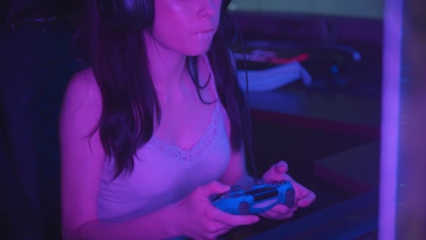 Junge Frau spielt Spiele in Neon-Spielclub und pustet einen Bubblegum - hält einen Steuerknüppel — Stockvideo