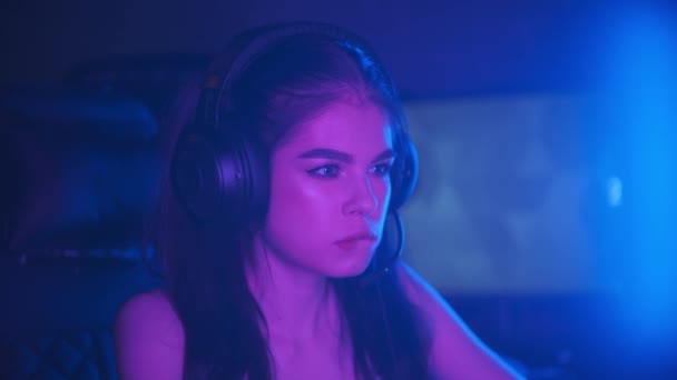 Young attractive woman sitting in neon gaming club and playing games - biting her lip - winning the game and gets happy — Stock Video