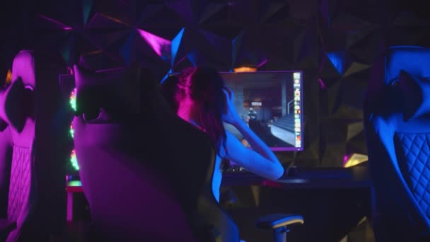 Jonge mooie vrouw zitten in neon gaming club en het spelen van games - staat op uit de stoel en loopt weg — Stockvideo