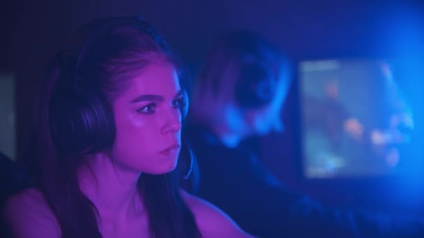 Två tjejer vänner spelar ett online-spel i neon gaming club - ge varandra och high five — Stockvideo