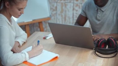 İngilizce sınıfı - bir kadın ve Afrikalı-Amerikalı erkek İngilizce dersi alıyor - erkek dizüstü bilgisayarın başında oturuyor ve kadın notlar alıyor